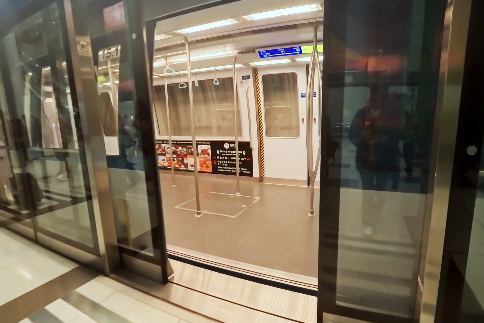 香港国際空港の無人運転シャトル(APM)の車内。ホームドアが開いた状態の無機質な近未来的デザインの車両