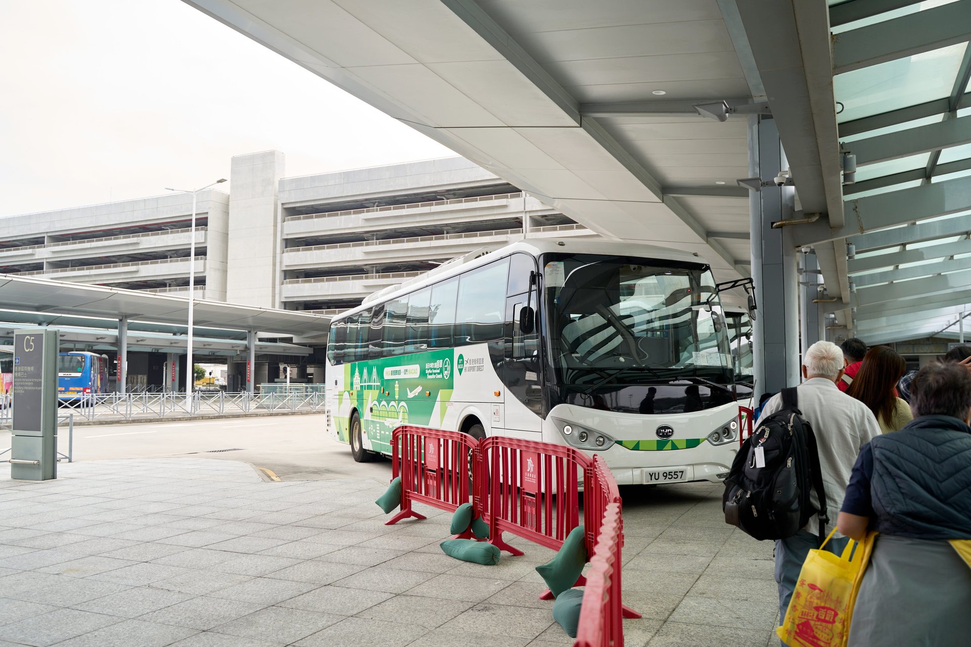 香港国際空港のバス乗り場。乗車を待つ乗客と停車中の白いバス