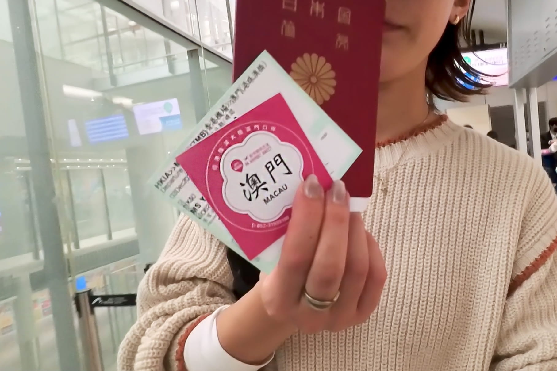 「澳門(MACAU)」と書かれたピンクのチケット、日本のパスポート、搭乗券を手に持つ女性。空港でのマカオ旅行の出発シーン